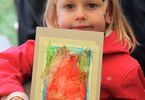 Dziewczynka pokazuje swoją pracę namalowaną flamastrami.