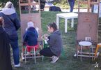 Instruktorka kuca obok dziecka rysującego na sztaludze.