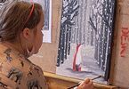 Dziewczynka przy sztaludze z pędzelkiem w ręku maluje kolejne elementy obrazu