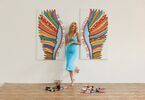 Zdjęcie autorki z kolorowymi skrzydłami namalowanymi na ścianie