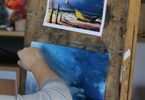 Obraz łodzi na plaży w trakcie malowania.