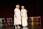 Dwie kobiety w średnim wieku ubrane na biało stoją na scenie.