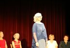 Kobiety w średnim wieku w kolorowych sukienkach stoją na scenie.