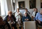 Seniorzy siedzą i słuchają wykładu.