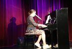 Młoda kobieta śpiewa na scenie przy pianinie