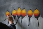 Ręka z pędzlem malująca ptaki z żółto-pomarańczowymi brzuszkami