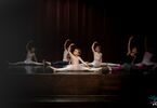 Baletnice na scenie wykonują szpagat z uniesionymi rękoma