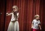 Dziewczynka gra na skrzypcach, na drugim planie chłopiec