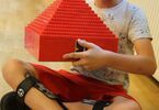 Chłopiec trzymający w dłoniach budowlę z klocków Lego