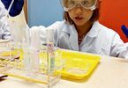 Dziewczynka obserwująca efekty dodania substancji do próbówki, z której wydobywa się piana