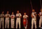 Grupa capoeiry na scenie, grająca na instrumentach brazylijskich