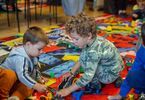 Dwaj chłopcy bawiący się kolejką zbudowaną z klocków Lego, jeżdżącą po torach stworzonych do zabawy