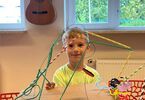 Chłopiec trzymający kreatywną pracę wykonaną przy pomocy różnych materiałów, jak na przykład słomek i sznurków