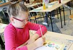 Dziewczynka malująca farbami akwarelowymi swoją zakładkę do książki