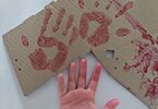Dłoń dziecka i karton z odbitymi dłońmi