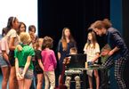 Muzyk prezentuje zgromadzonym w okręgu dzieciom instrumentarium