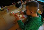 Chłopiec malujący farbami maskę wyciętą z wytłaczanek po jajkach