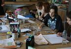 Uczestnicy Art-Geo zgromadzeni przy stole z narzędziami do malowania