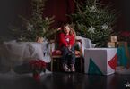 Dziewczynka pozująca do zdjęcia na świątecznym tle w formie choinek z lampkami, prezentów, siedząca na świątecznym fotelu i pufach DK Zacisze