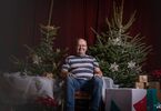 Instruktor tańca w DK Zacisze pozujący do zdjęcia na świątecznym tle w formie choinek z lampkami, prezentów, siedzący na świątecznym fotelu i pufach DK Zacisze