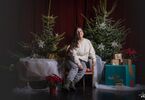 kobieta pozująca do zdjęcia na świątecznym tle w formie choinek z lampkami, prezentów, siedząca na świątecznym fotelu i pufach DK Zacisze