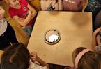 Eksperyment z kolorowymi cukierkami na stole, wokół dzieci