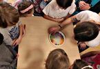 Eksperyment z kolorowymi cukierkami na stoliku, wokół dzieci i prowadząca