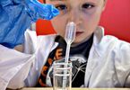 Chłopiec obserwujący próbówkę chemiczną