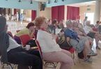 Seniorzy siedzą  i oglądają prezentację