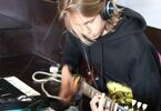Chłopak w czarnej bluzie i słuchawkach gra na gitarze elektronicznej