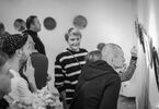 Zdjęcie czarno-białe. Ludzie zwiedzający wystawę talerzy ceramicznych.