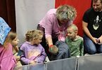 Kobieta w różowej bluzce trzyma na ręku jeża i pokazuje dzieciom