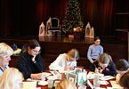 Kobiety i dziewczynki siedzące przy okrągłym stole podczas warsztatów świątecznych