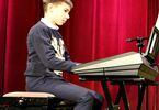 Chłopiec w swetrze renifera na pianinie elektronicznym