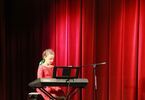 Dziewczynka w czerwonej sukience gra na pianinie elektronicznym