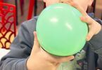 Chłopiec pompuje zielony balon