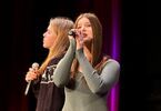 Dwie dziewczynki śpiewają do mikrofonów na scenie