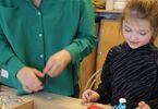 Kobieta w zielonej bluzce i dziewczynka podczas warsztatów tworzenia kompozycji w pudełku