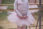 Dziewczynka w stroju baletnicy stoi na parkiecie, w tle lustra