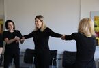 Trzy kobiety ubrane na czarno trzymają się za ręce