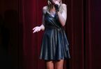 Nastolatka śpiewająca na scenie w czarnej sukience