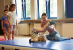Kobieta  asystująca dzieciom podczas zajęć akrobatyki