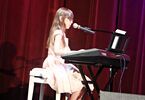 Dziewczynka w białej sukience przy pianinie elektronicznym