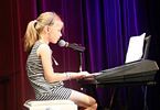 Dziewczynka w sukience w paski grająca na pianinie