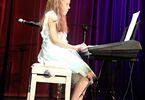 Dziewczynka w białej sukience, z długimi włosami przy pianinie
