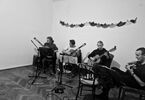 Foto czarno-białe, czterech muzyków gra na gitarze