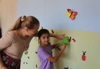 Kobieta z dziewczynką przyklejające kolorowe motyle na ścianie