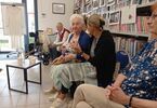 Zdjęcie: Seniorzy siedzą pod regałem z książkami