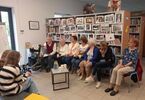 Zdjęcie: Seniorzy siedzą pod regałem z książkami