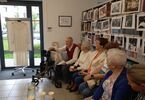 Zdjęcie: Seniorzy siedzą pod regałem z książkami